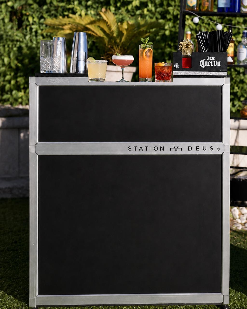 Postazione mobile Station Deus di Night Wave, vista frontalmente all’aperto, con cocktail, shaker e bicchieri sul banco.